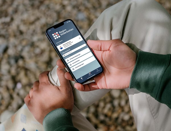 Vårdapp i handen på man utomhus