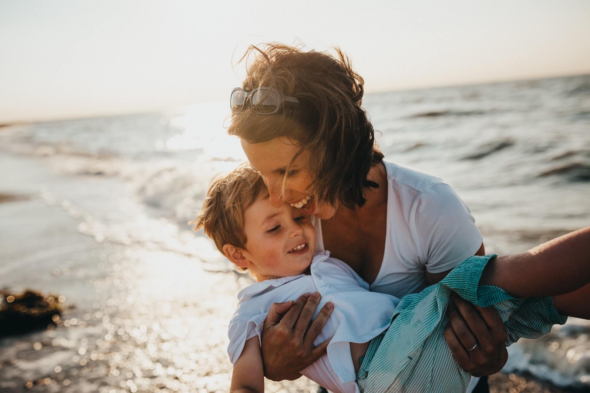Woman carrying young boy at the beach